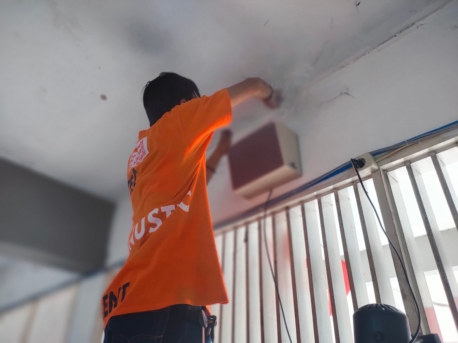 Teknisi memasang speaker paging system di sekolah